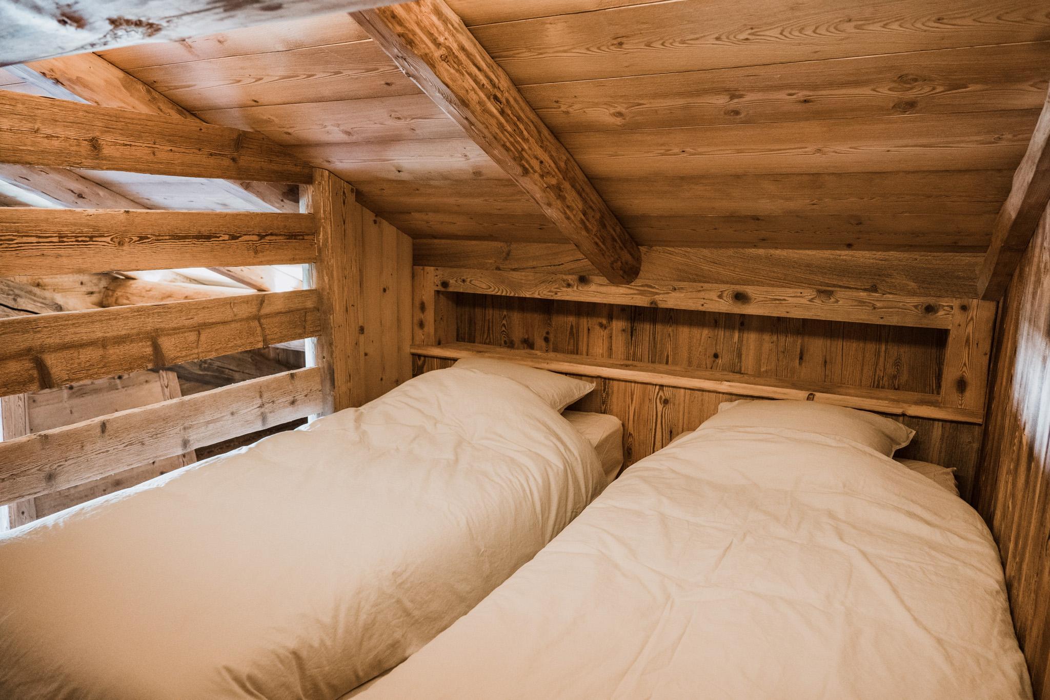 Alcôve de couchage en vieux bois nichée sous la charpente de la ferme d'alpage