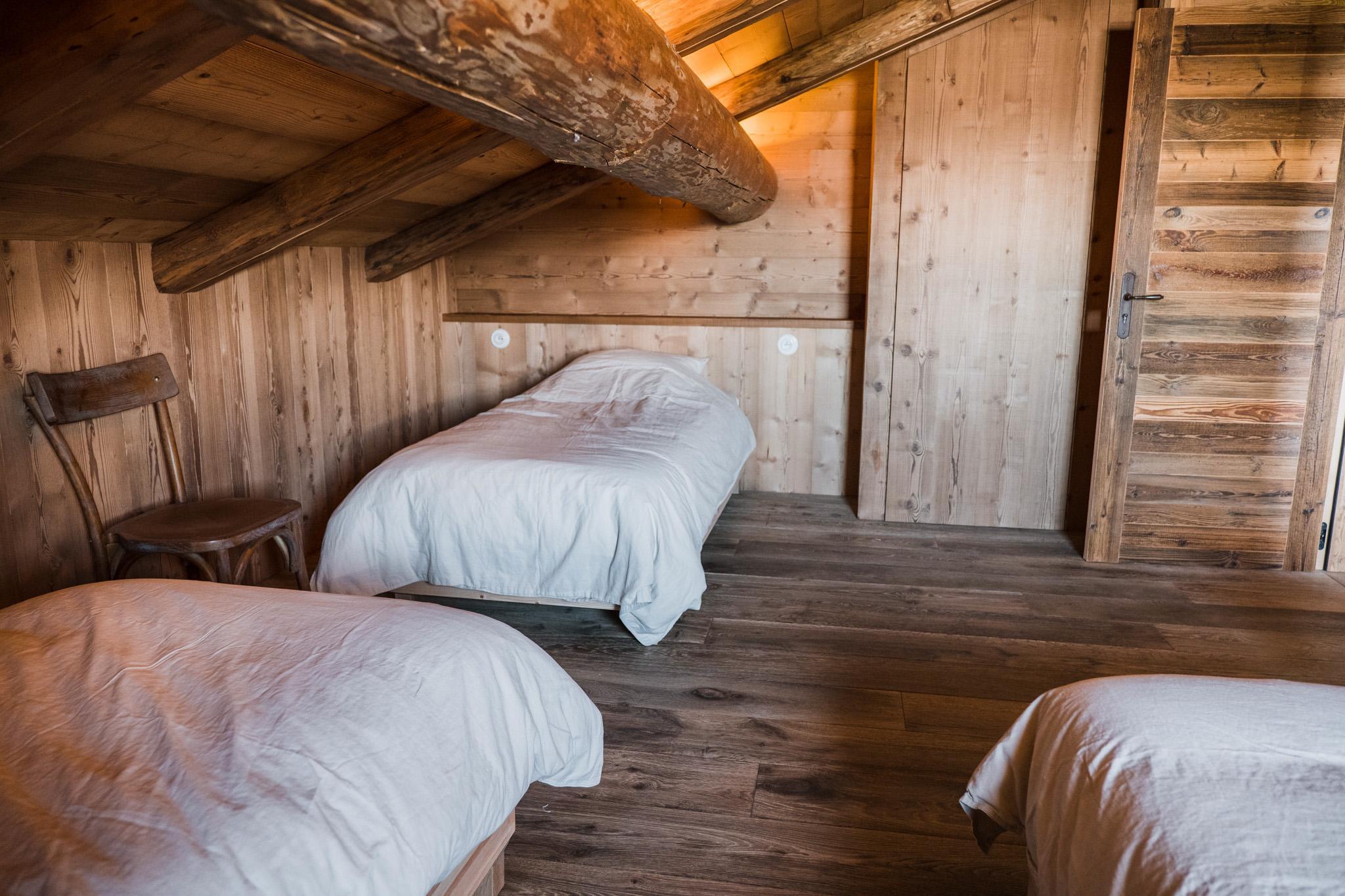 Chambre mansardée en vieux bois de la ferme d'alpage, lits individuels sous la charpente
